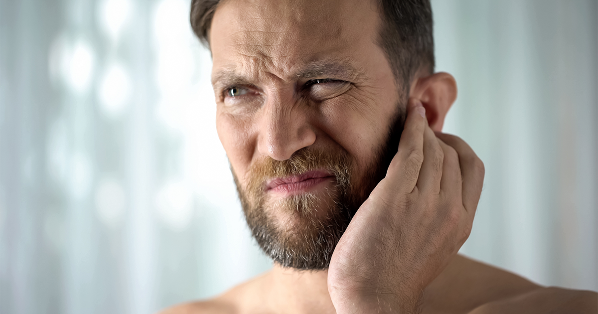 Person scratching ear with discomfort due to itchy ear canal