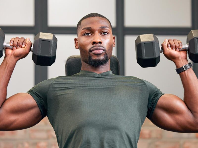 Man lifting dumbbells during a muscle building workout at the gym