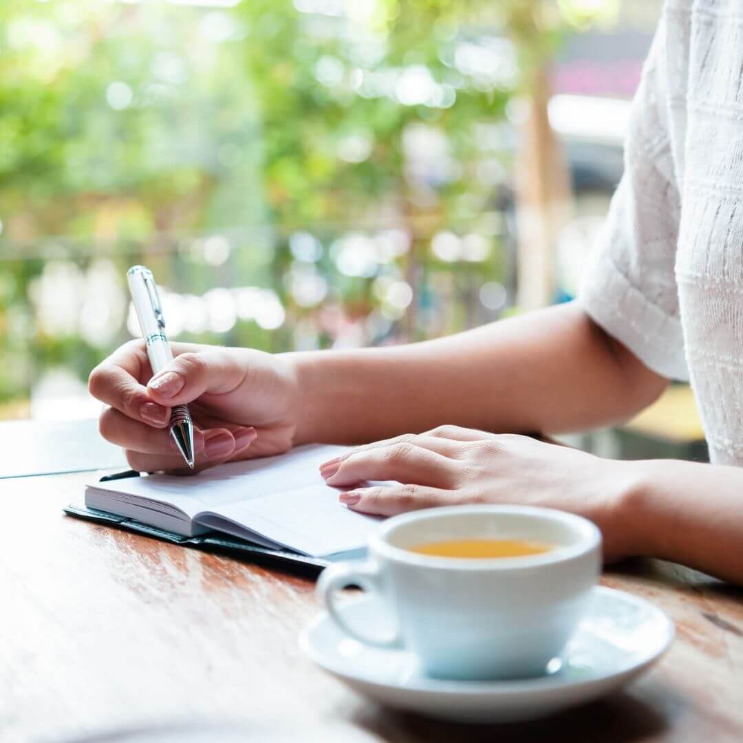 Woman journaling with a cup of tea