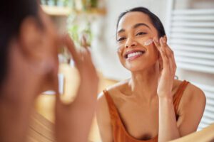 Woman applying lotion to her face under bright sunlight