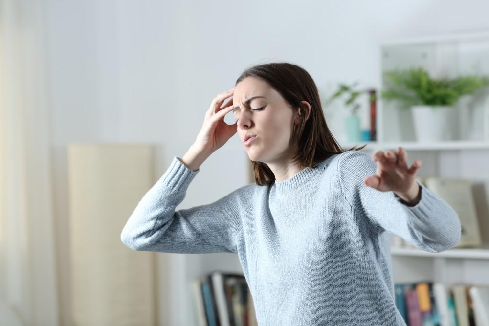 Woman holding her head, experiencing the vertigo and dizziness